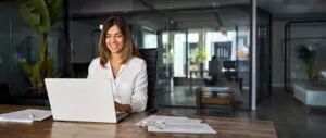 woman writing content on her computer whilst smiling