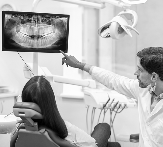 Image of a dentist with a patient pointing at an x-ray to represent the Dental Law case study