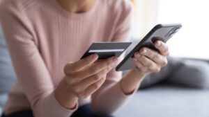 person holding phone and credit card, about to purchase a product online