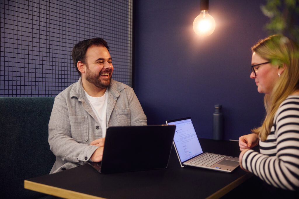 Sam Thomas laughing and working in the Embryo Manchester office