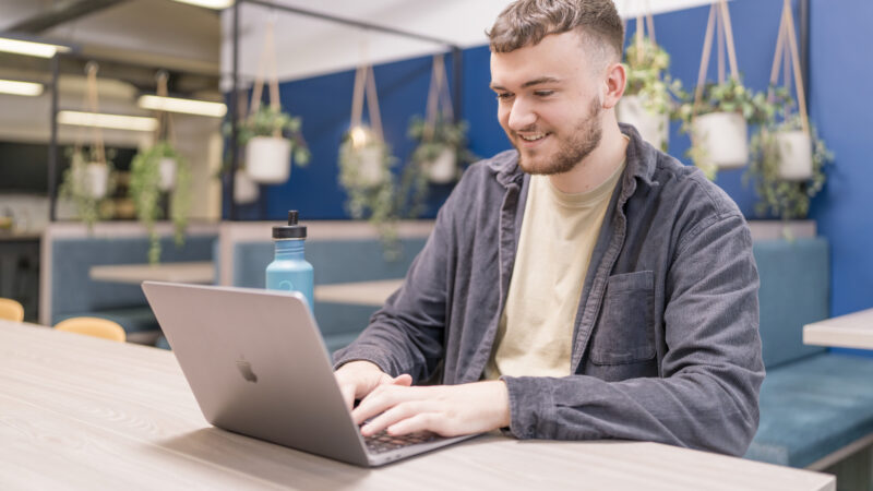 callum leonard, paid media director at embryo, working on his laptop in the office