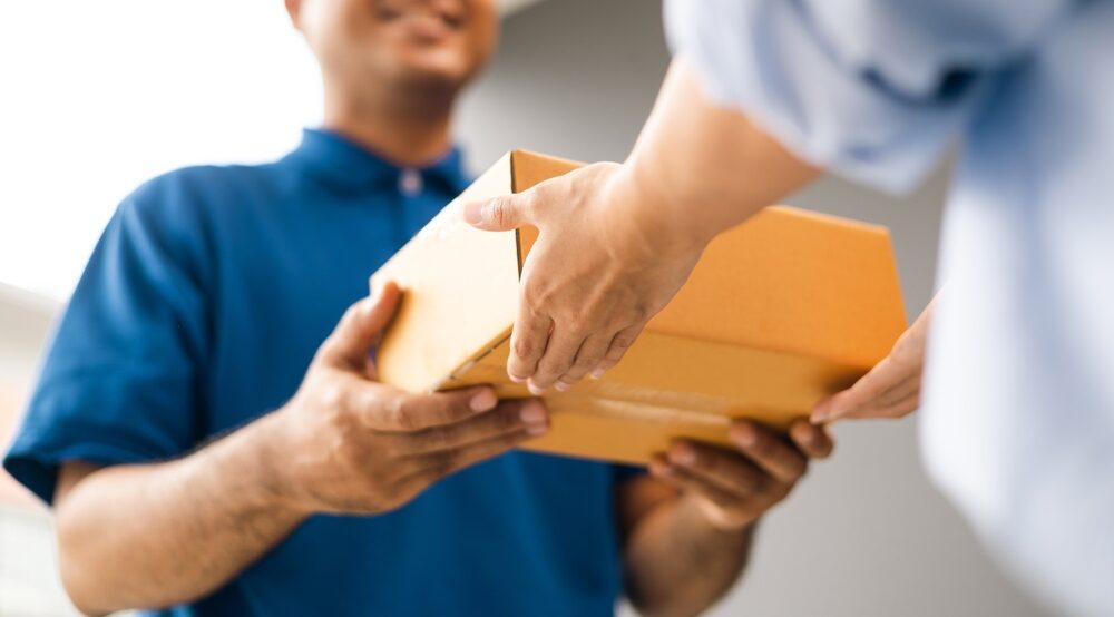 Close,Up,Parcel,In,Hand,Of,Blue,Uniform,Delivery,Man