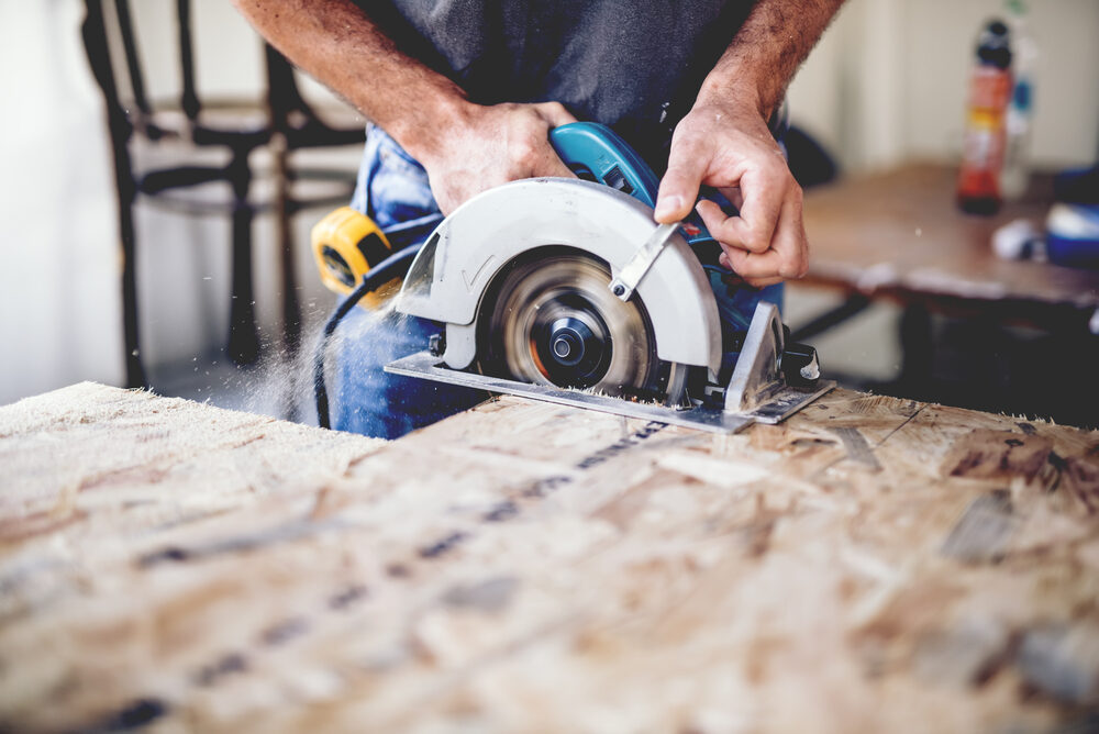 Man cutting through wood in a workshop using a circular saw